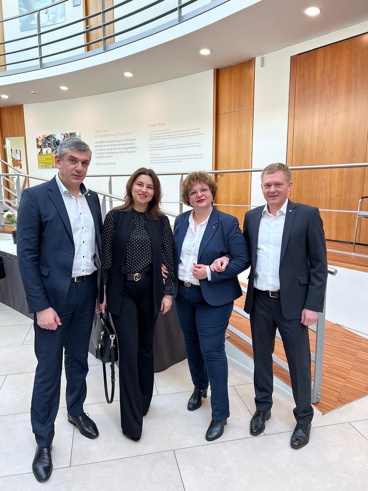 Larissa Etzel mit drei weiteren Personen in Geschäftskleidung in einem hellen Foyer.