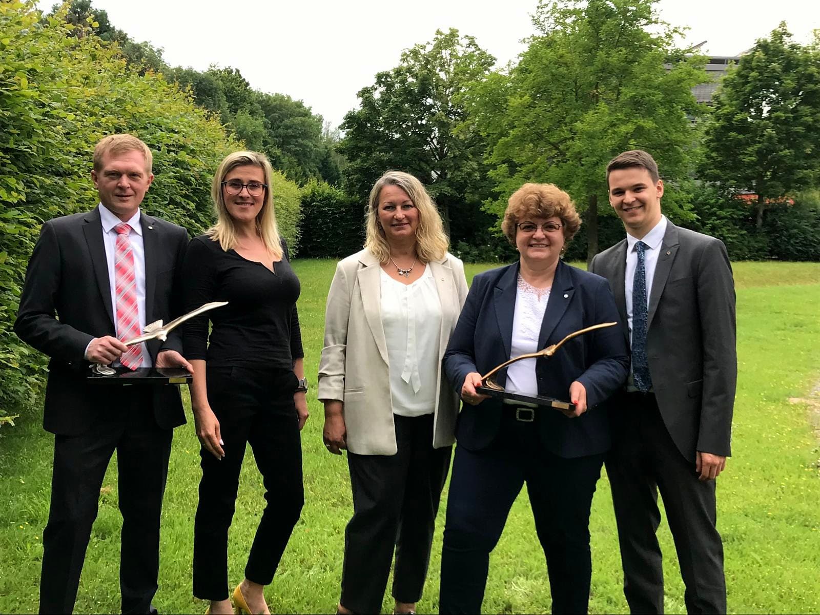 Larissa Etzel mit vier weiteren Personen auf einer Wiese, zwei von ihnen halten eine gläserne Trophäe.