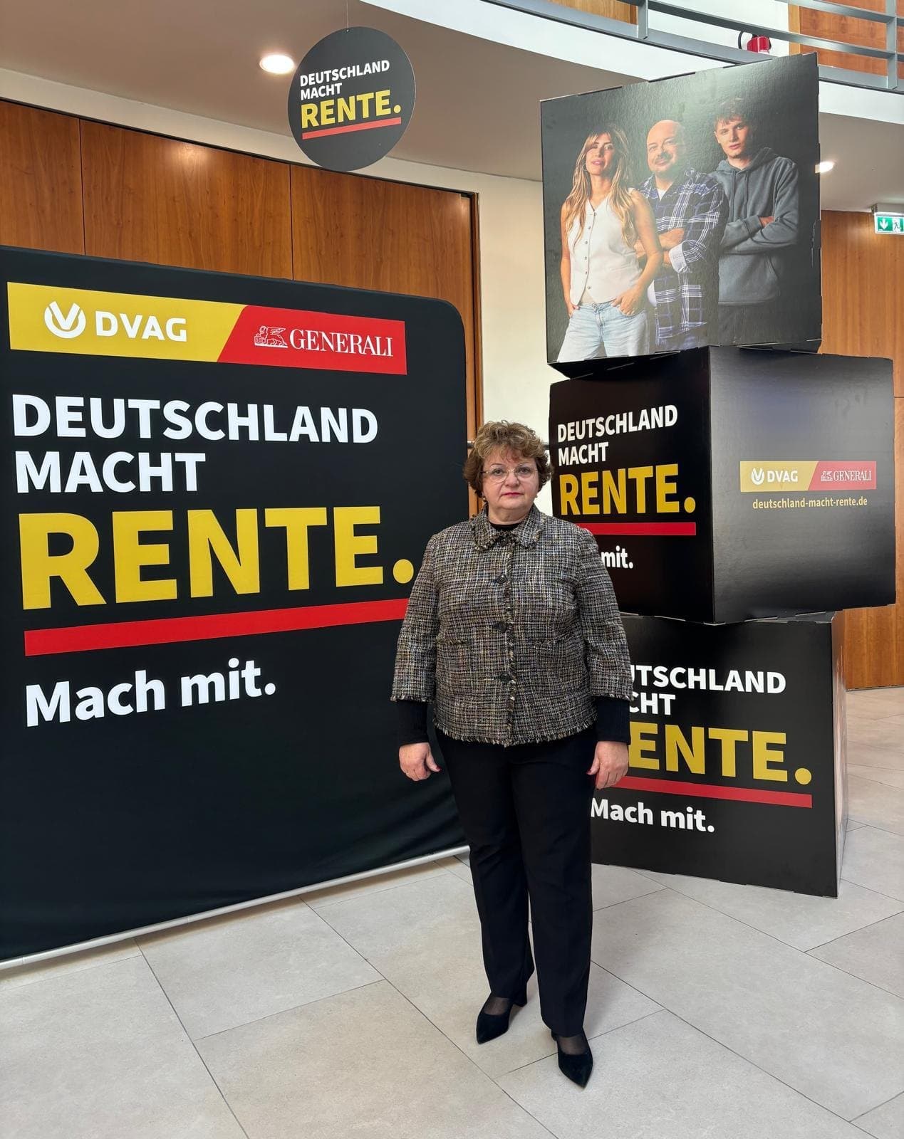 Larissa Etzel steht vor Aufstellern der Kampagne „Deutschland macht Rente. Mach mit.“ von DVAG und Generali.